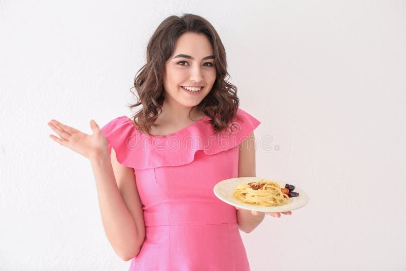 Молодая женщина с плитой вкусных макаронных изделий на белой предпосылке стоковая фотография rf Молодая женщина с плитой вкусных макаронных изделий на белой предпосылке стоковая фотография rf
