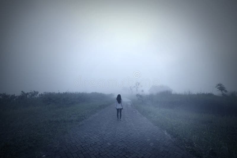 Rear view of young woman standing alone on the path at misty morning. Rear view of young woman standing alone on the path at misty morning