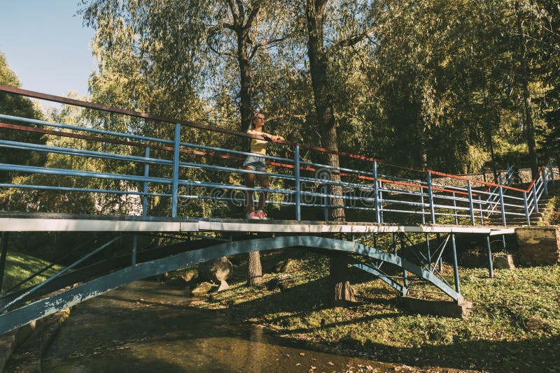 Молодая женщина, стоящая у красивой реки летом, наслаждается отдыхом на природе в горной местности, на реке и на мосту стоковое изображение rf Молодая женщина, стоящая у красивой реки летом, наслаждается отдыхом на природе в горной местности, на реке и на мосту стоковое изображение rf