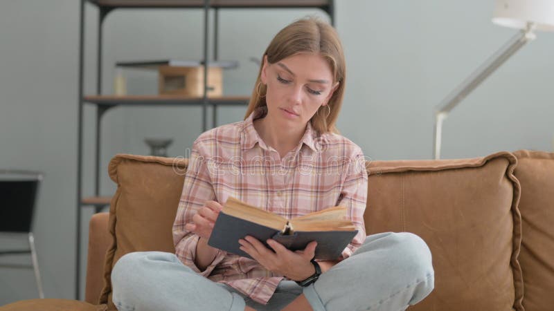 молодая женщина читает книгу, сидя в постели сток-видео