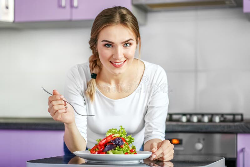 Молодая здоровая девушка ест vegetable салат счастливая домашняя женщина стоковое изображение rf Молодая здоровая девушка ест vegetable салат счастливая домашняя женщина стоковое изображение rf