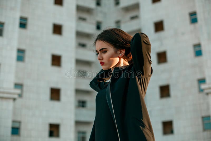 Молодая красивая девушка в черной куртке представляя против фона высокого Белого Дома стоковые фото Молодая красивая девушка в черной куртке представляя против фона высокого Белого Дома стоковые фото