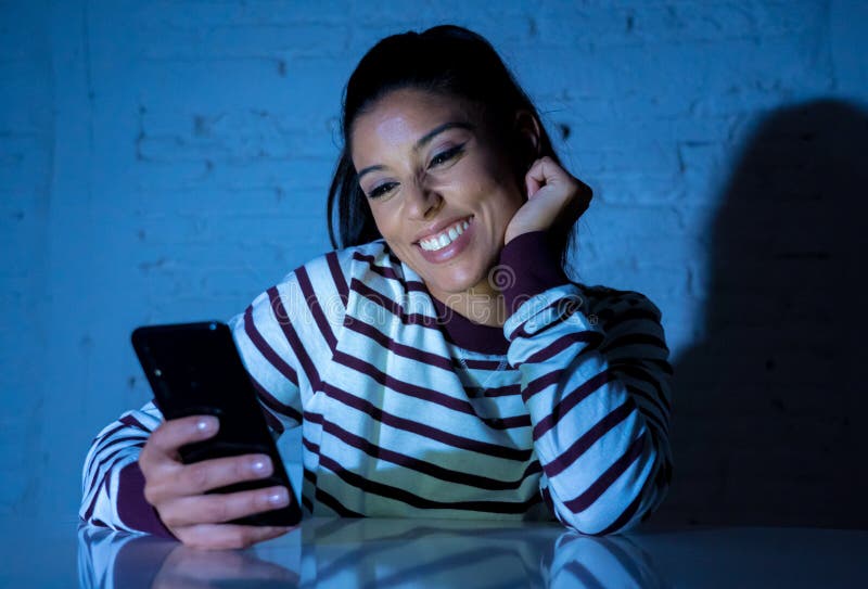 Молодая красивая женщина flirting и беседуя на ее умном телефоне поздно на ноче стоковое фото rf Молодая красивая женщина flirting и беседуя на ее умном телефоне поздно на ноче стоковое фото rf