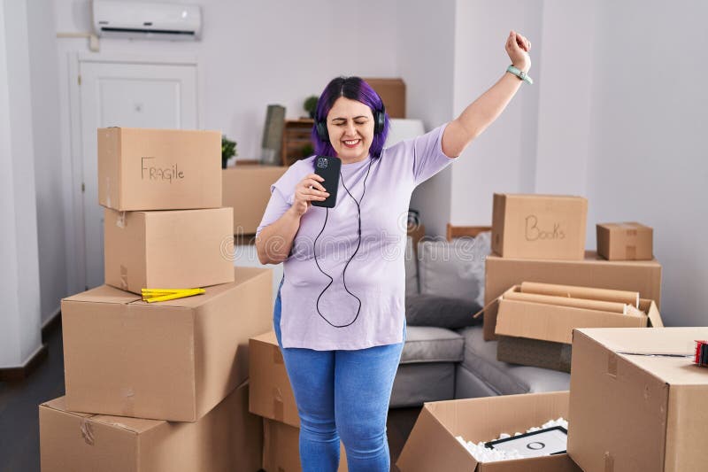 молодая красивая женщина plus size, которая слушает музыку, танцуя в новом доме стоковые изображения rf