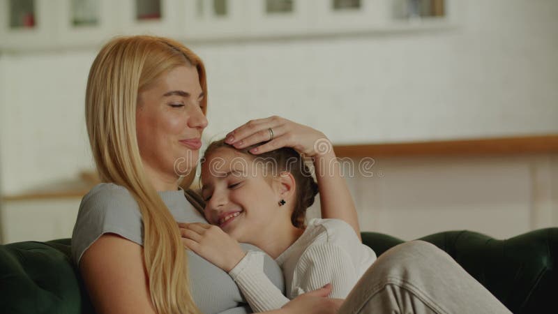 молодая мать и растущая дочь нежно обнимались на диване дома. проявление материнской нежности и любви.