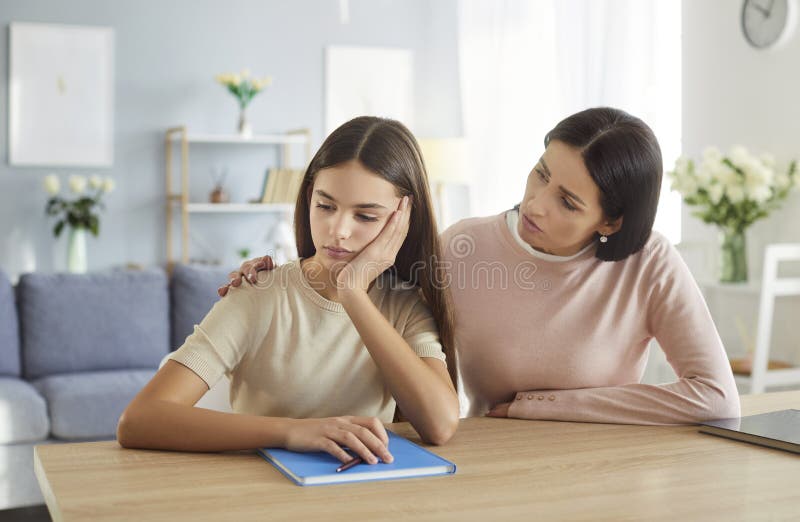 Молодая мать поддерживает свою дочь-подростка, уставшую от школьных домашних заданий стоковые изображения rf