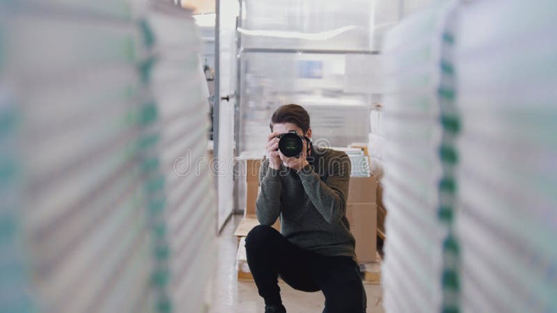 Молодая мужская профессиональная стрельба фотографа перед бумажными стогами в оформлении стоковые изображения Молодая мужская профессиональная стрельба фотографа перед бумажными стогами в оформлении стоковые изображения
