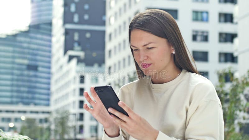 молодая привлекательная женщина с беспроводными наушниками слушает музыку через мобильный телефон. современная европея акции видеоматериалы