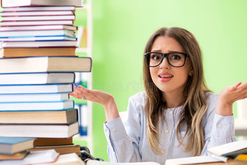 Молодая студентка подготавливая для экзаменов с много книг стоковые фото Молодая студентка подготавливая для экзаменов с много книг стоковые фото