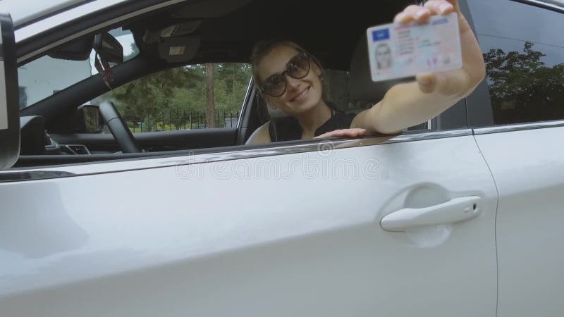 Молодая счастливая женщина показывая ее новые водительские права
