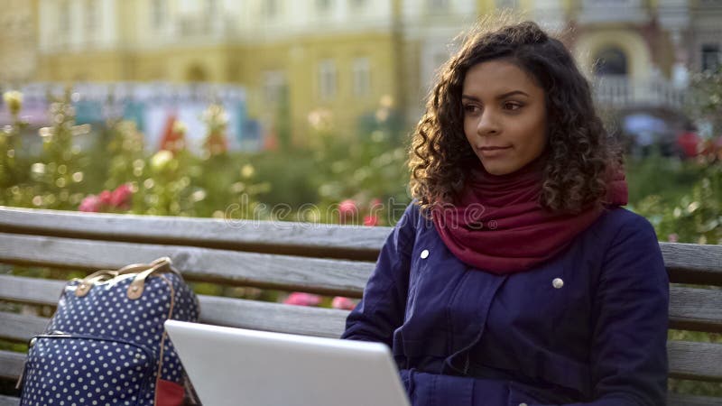 Молодой biracial писатель работая на новом проекте, сидя с компьтер-книжкой outdoors стоковая фотография Молодой biracial писатель работая на новом проекте, сидя с компьтер-книжкой outdoors стоковая фотография