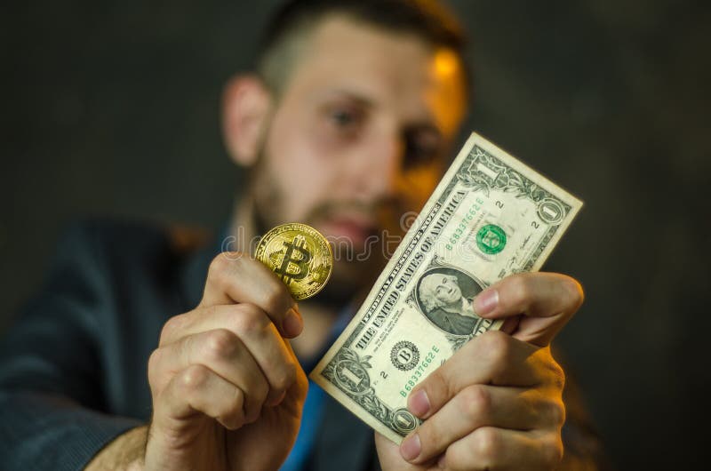 Молодой бизнесмен держит монетку bitcoite в его руке стоковое изображение rf Молодой бизнесмен держит монетку bitcoite в его руке стоковое изображение rf