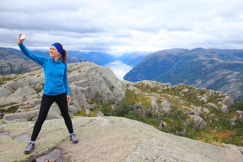 Молодой красивый hiker принимая selfie на ее пути к саммиту утеса Preikestolen амвона, муниципалитета Forsand стоковое фото