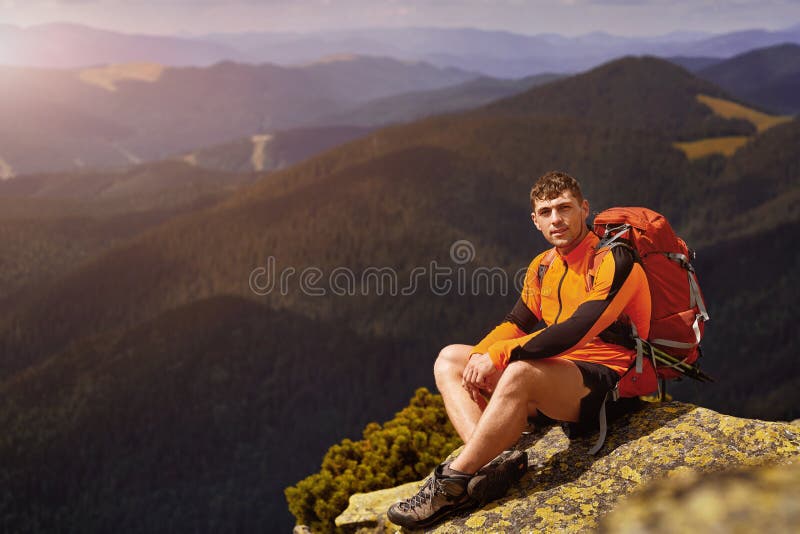 Молодой мужской hiker при рюкзак ослабляя na górze горы во время спокойного захода солнца лета стоковое изображение Молодой мужской hiker при рюкзак ослабляя na górze горы во время спокойного захода солнца лета стоковое изображение