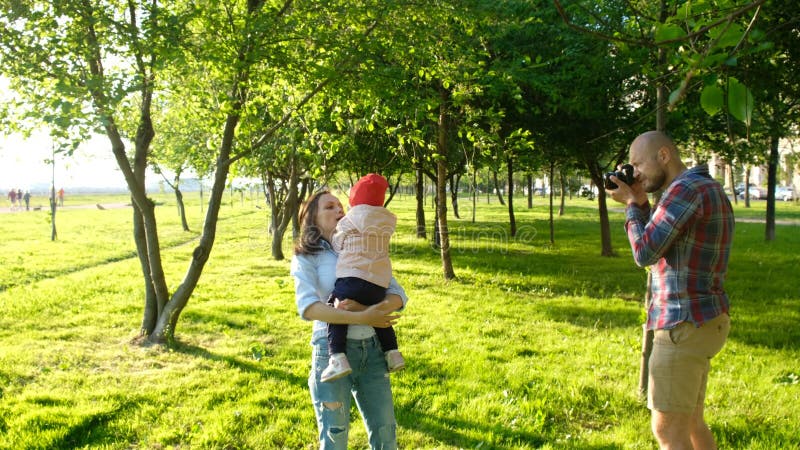 Молодой отец фотографируя мать и дочь играя в парке на заходе солнца Счастливая семья имея остатки и стоковое изображение rf Молодой отец фотографируя мать и дочь играя в парке на заходе солнца Счастливая семья имея остатки и стоковое изображение rf