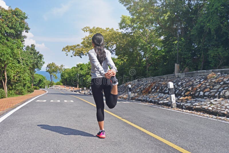 Молодой подогрев бегуна женщины фитнеса на дороге перед jogging стоковое фото