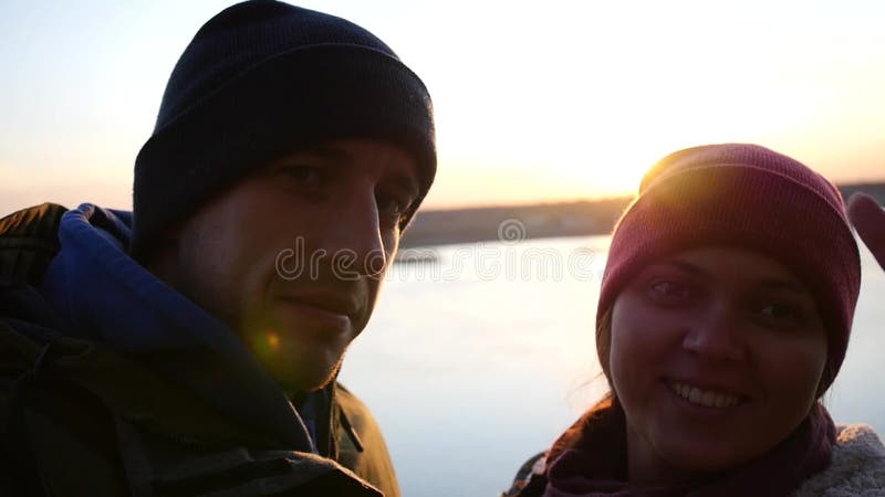 Молодой человек пар и женщина сфотографированные рекой на предпосылке захода солнца в осени, выставка в камере
