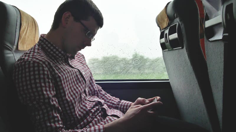 Молодой человек проверяя электронные почты на его коммутирует к работе автобусом в длинном отключении Конец-вверх использования м стоковое изображение Молодой человек проверяя электронные почты на его коммутирует к работе автобусом в длинном отключении Конец-вверх использования м стоковое изображение