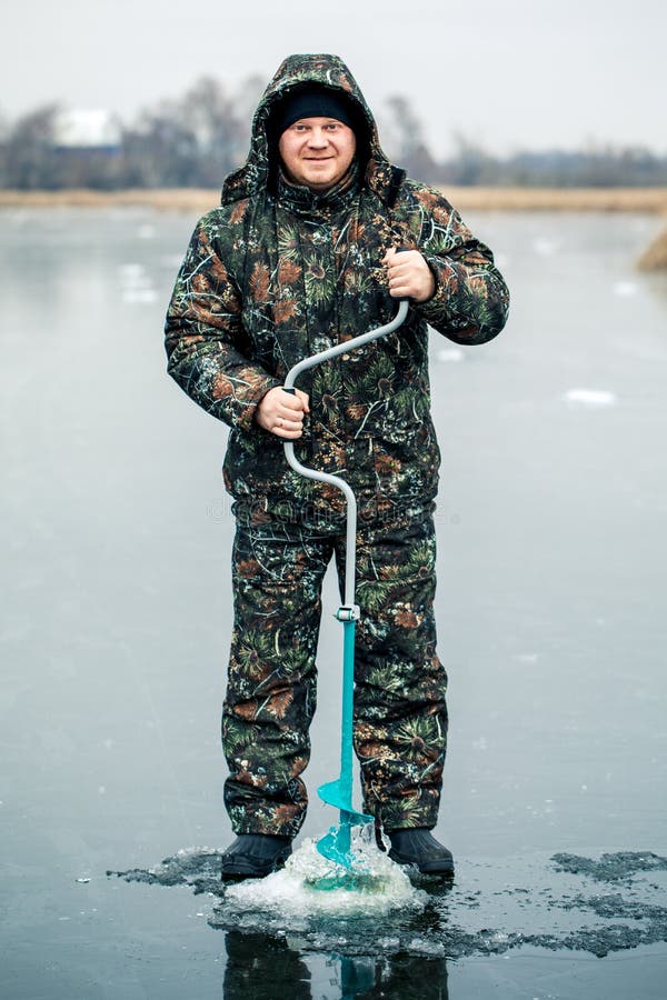 Молодой человек рыбачит из ямы на льду Зимняя рыбная ловля