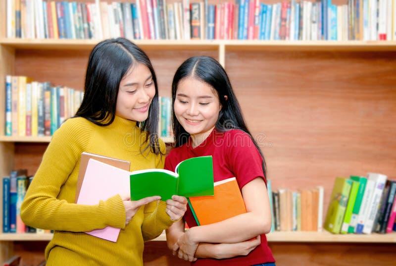 Молодые азиатские книги чтения студента колледжа в острословии библиотеки стоковая фотография rf Молодые азиатские книги чтения студента колледжа в острословии библиотеки стоковая фотография rf