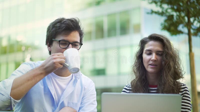 Молодые деловые партнеры обсуждая их работу в кофе кафа лета выпивая