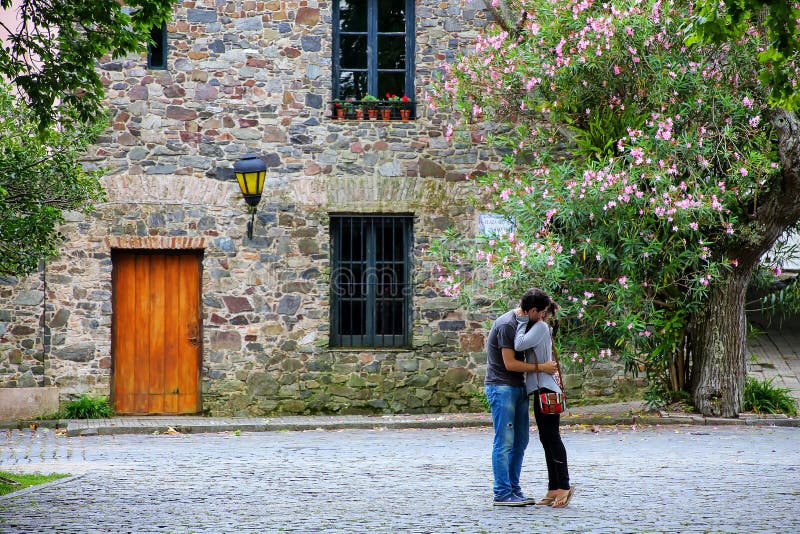 Молодые пары обнимая перед старым домом в Colonia del Sac стоковые изображения rf Молодые пары обнимая перед старым домом в Colonia del Sac стоковые изображения rf