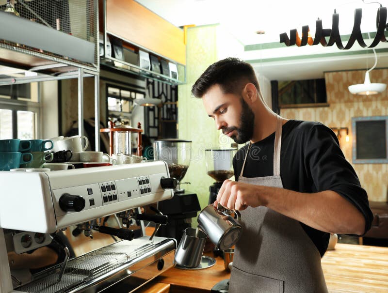 Молоко Barista лить в кувшин металла около машины кофе стоковая фотография rf Молоко Barista лить в кувшин металла около машины кофе стоковая фотография rf