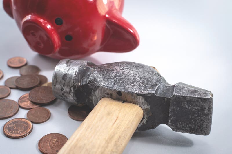 A hammer and a broken red piggy bank, next to a pile of small euro coins. The concept of finding money, shopping, crisis, poverty, payment. A hammer and a broken red piggy bank, next to a pile of small euro coins. The concept of finding money, shopping, crisis, poverty, payment.