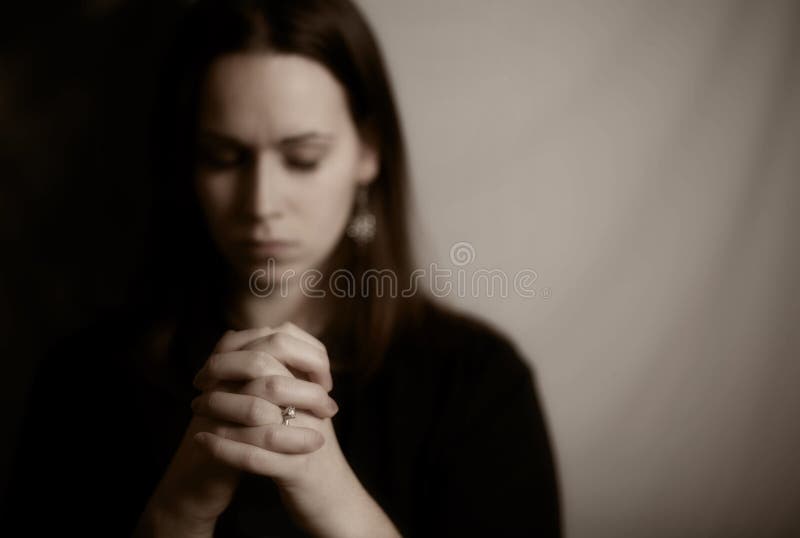 A brunette woman praying with her hands together. A brunette woman praying with her hands together