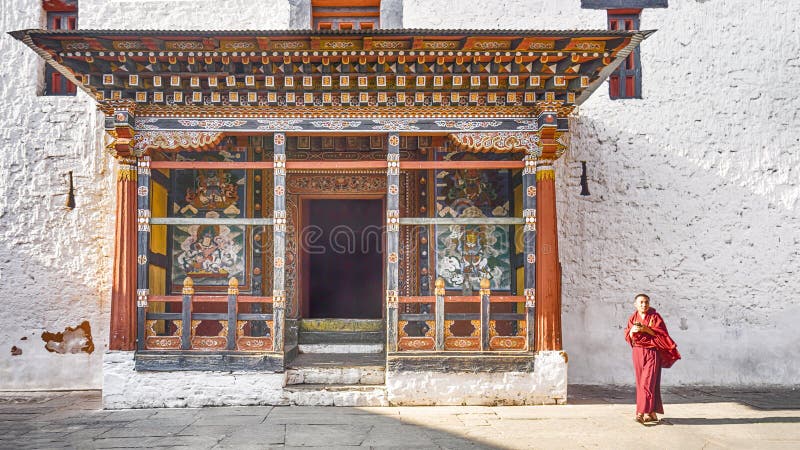 Монах человека Азии идет около молитвы башни входной двери на Paro Dzong, стоковая фотография rf Монах человека Азии идет около молитвы башни входной двери на Paro Dzong, стоковая фотография rf