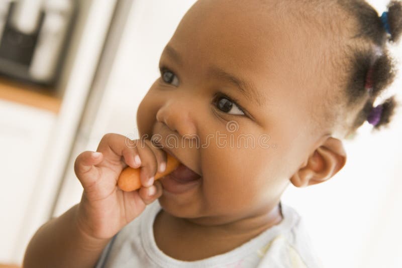 Close up of Young girl eating carrot indoors. Close up of Young girl eating carrot indoors