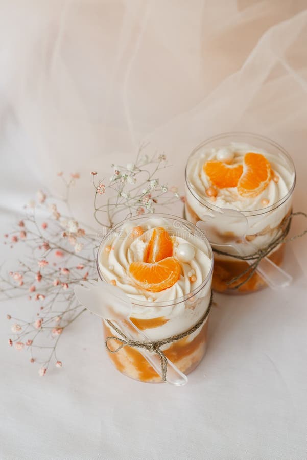 2 ice creams in a transparent cup decorated with tangerines on a white table. 2 ice creams in a transparent cup decorated with tangerines on a white table