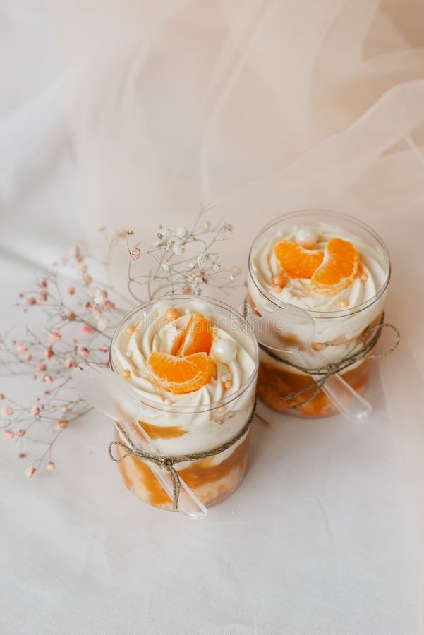 2 ice creams in a transparent cup decorated with tangerines on a white table. 2 ice creams in a transparent cup decorated with tangerines on a white table