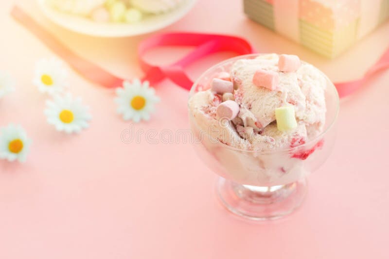 мороженое в чашке рядом с зефирами, цветки, розовые помадки стоковое изображение