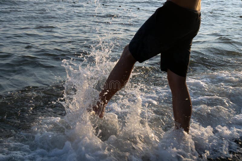 Male foot hits the water in the sea. Splashing water. Male foot hits the water in the sea. Splashing water