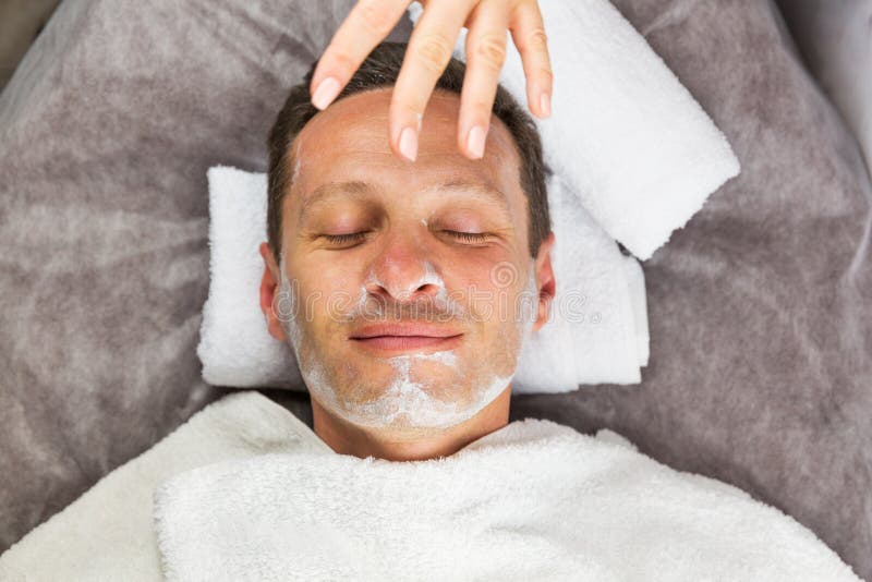Мужская сторона с cream маской, руками профессионального beautician стоковое фото rf Мужская сторона с cream маской, руками профессионального beautician стоковое фото rf