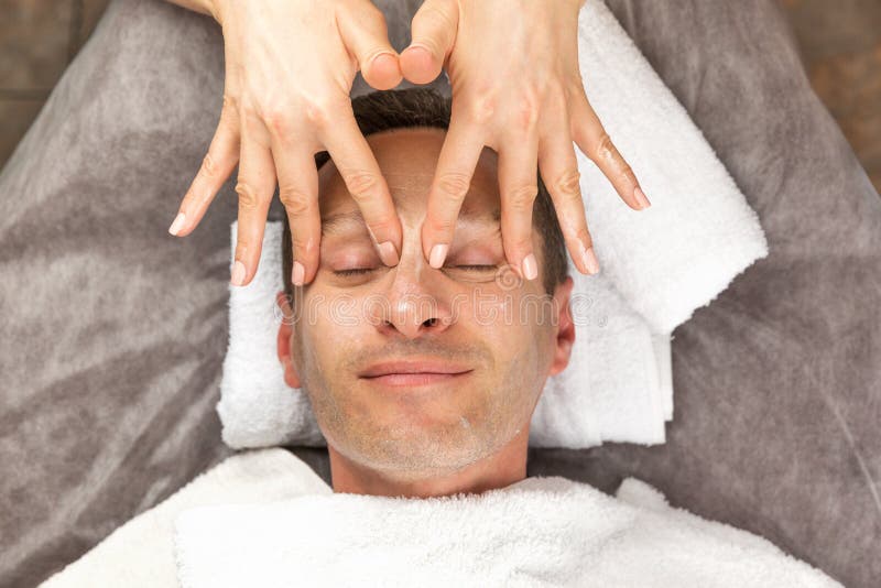 Мужская сторона с cream маской, руками профессионального beautician стоковое фото rf Мужская сторона с cream маской, руками профессионального beautician стоковое фото rf