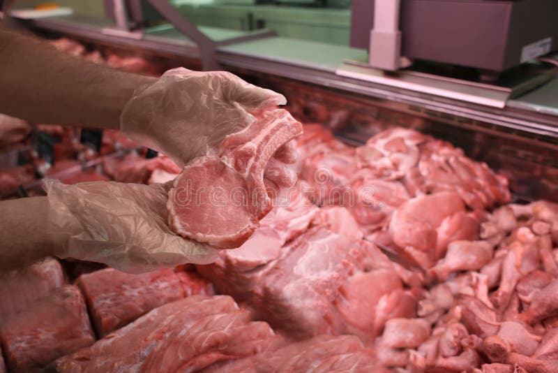 Мужская часть удерживания продавца свежего мяса в мясной лавке стоковая фотография Мужская часть удерживания продавца свежего мяса в мясной лавке стоковая фотография