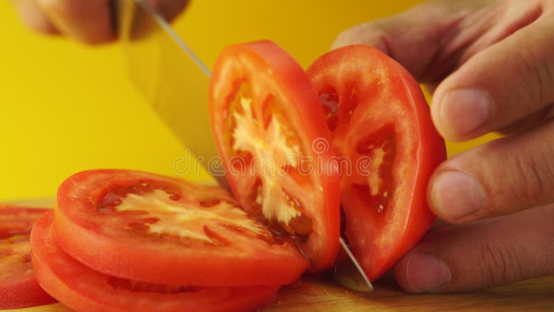 Мужские руки отрезая красные зрелые томаты