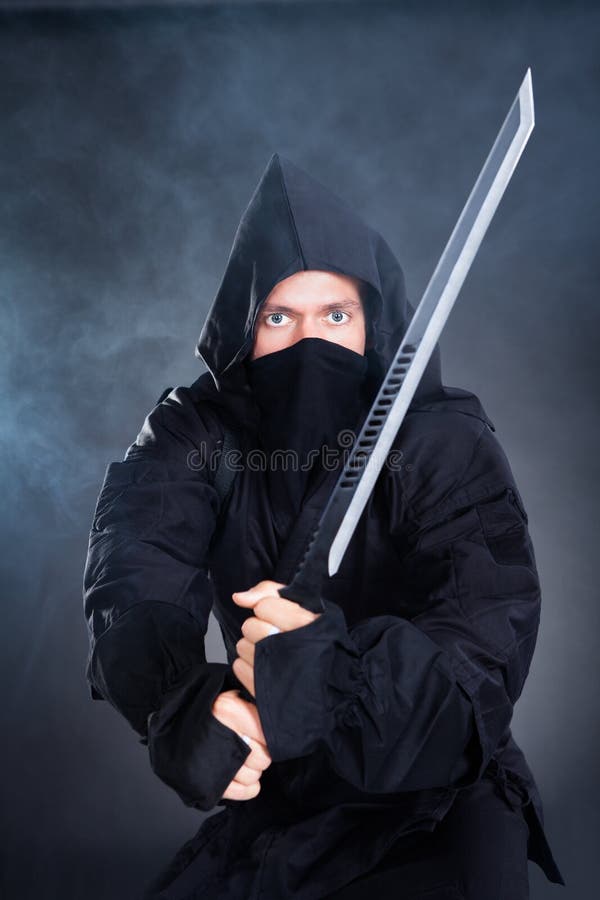Мужское Ninja в черном костюме держа шпагу стоковые фото Мужское Ninja в черном костюме держа шпагу стоковые фото