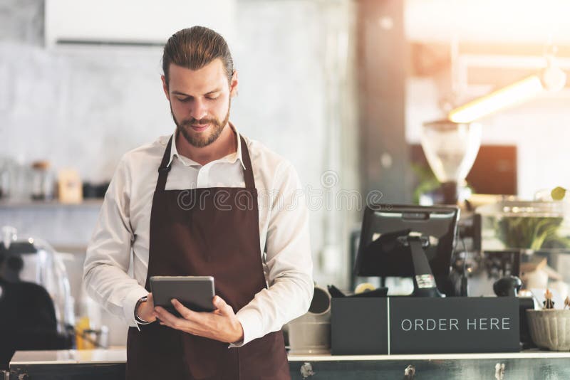 Мужское удерживание barista и смотреть цифровой планшет стоковые фотографии rf Мужское удерживание barista и смотреть цифровой планшет стоковые фотографии rf