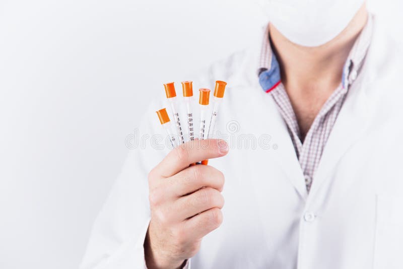 Мужской endocrinologist доктора в маске держа 5 шприцев инсулина на белой предпосылке стоковые фото Мужской endocrinologist доктора в маске держа 5 шприцев инсулина на белой предпосылке стоковые фото