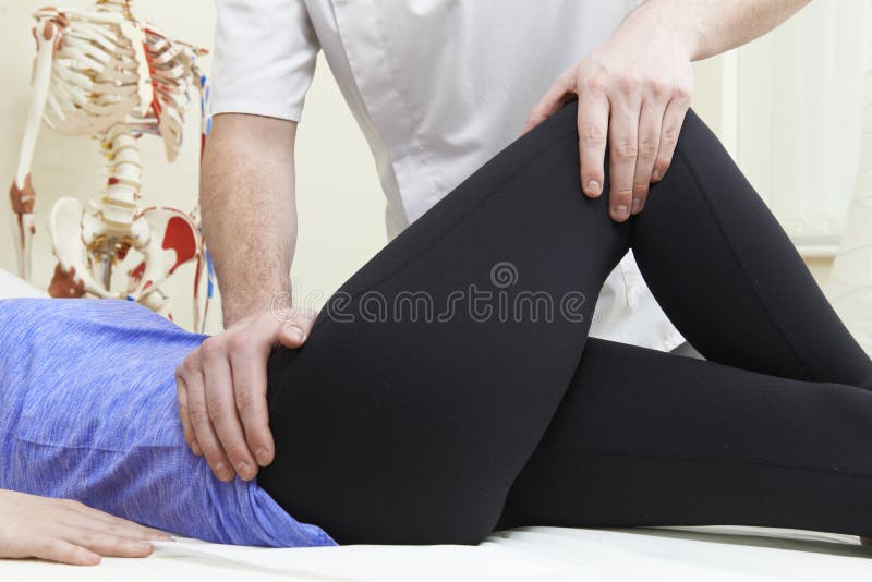 Мужской Osteopath обрабатывая женского пациента с тазобедренной проблемой стоковая фотография rf Мужской Osteopath обрабатывая женского пациента с тазобедренной проблемой стоковая фотография rf