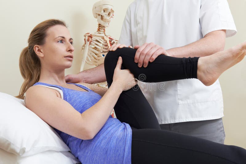 Мужской Osteopath обрабатывая женского пациента с тазобедренной проблемой стоковые изображения Мужской Osteopath обрабатывая женского пациента с тазобедренной проблемой стоковые изображения