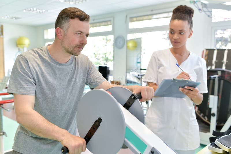 Мужской пациент при женский physio терапевт разрабатывая оружия стоковое изображение Мужской пациент при женский physio терапевт разрабатывая оружия стоковое изображение