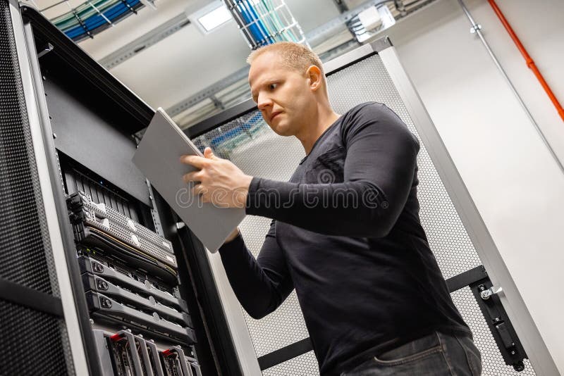 Мужской техник используя планшет цифров в Datacenter для того чтобы контролировать САН и серверы стоковое изображение Мужской техник используя планшет цифров в Datacenter для того чтобы контролировать САН и серверы стоковое изображение