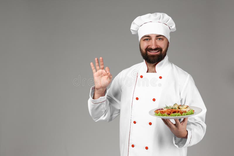 Мужской шеф-повар с вкусным блюдом на серой предпосылке стоковая фотография rf