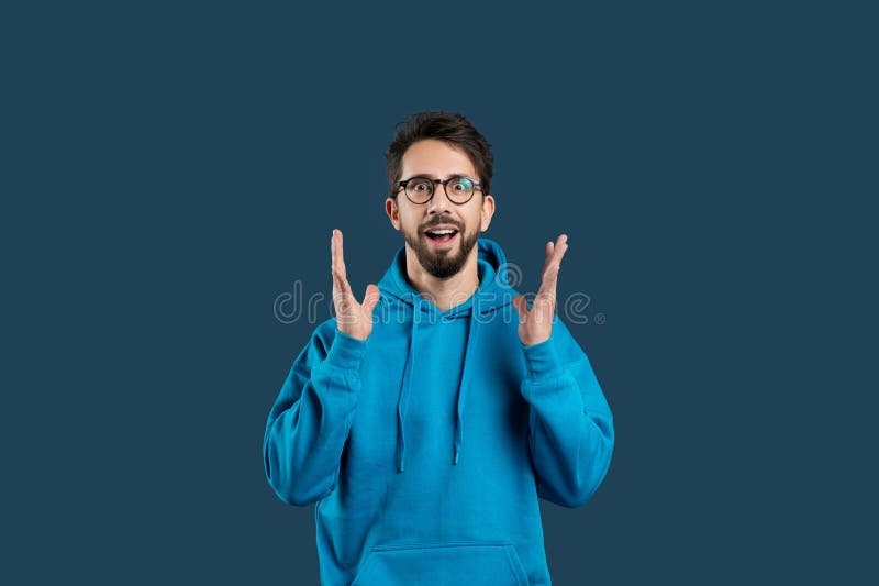 A man wearing a blue hoodie is seen gesturing with his hand in this photograph. The gesture appears to be deliberate and expressive, drawing attention to his actions. A man wearing a blue hoodie is seen gesturing with his hand in this photograph. The gesture appears to be deliberate and expressive, drawing attention to his actions.