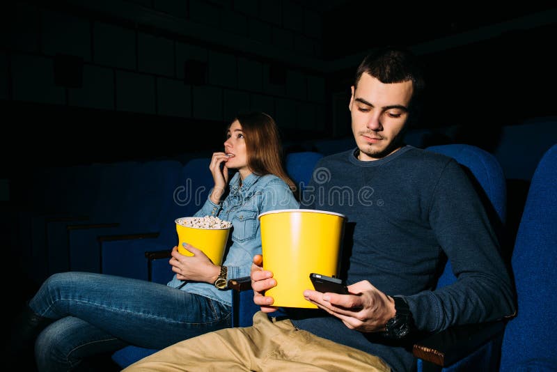 Мужчина, использующий смартфон во время просмотра фильма в кино стоковая фотография rf