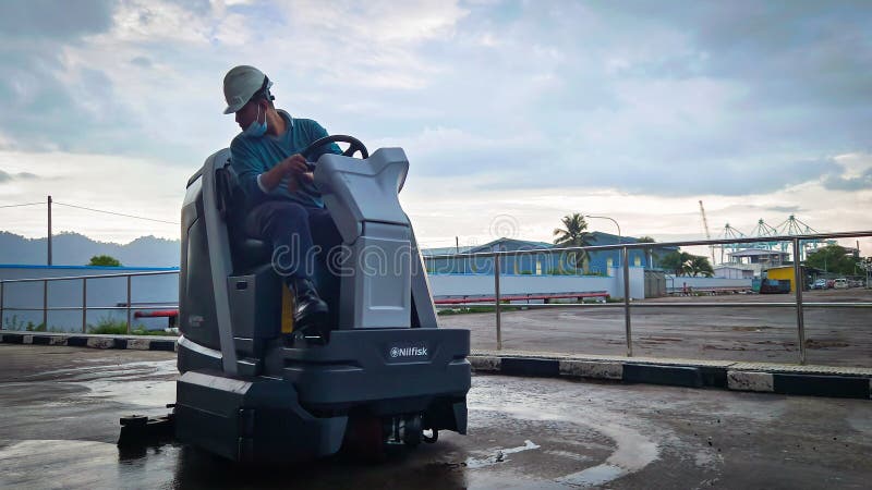 Lumut, Perak - April 2 2024: A man is cleaning a cement floor using a floor cleaning machine in a cemented area in a factory. Lumut, Perak - April 2 2024: A man is cleaning a cement floor using a floor cleaning machine in a cemented area in a factory.